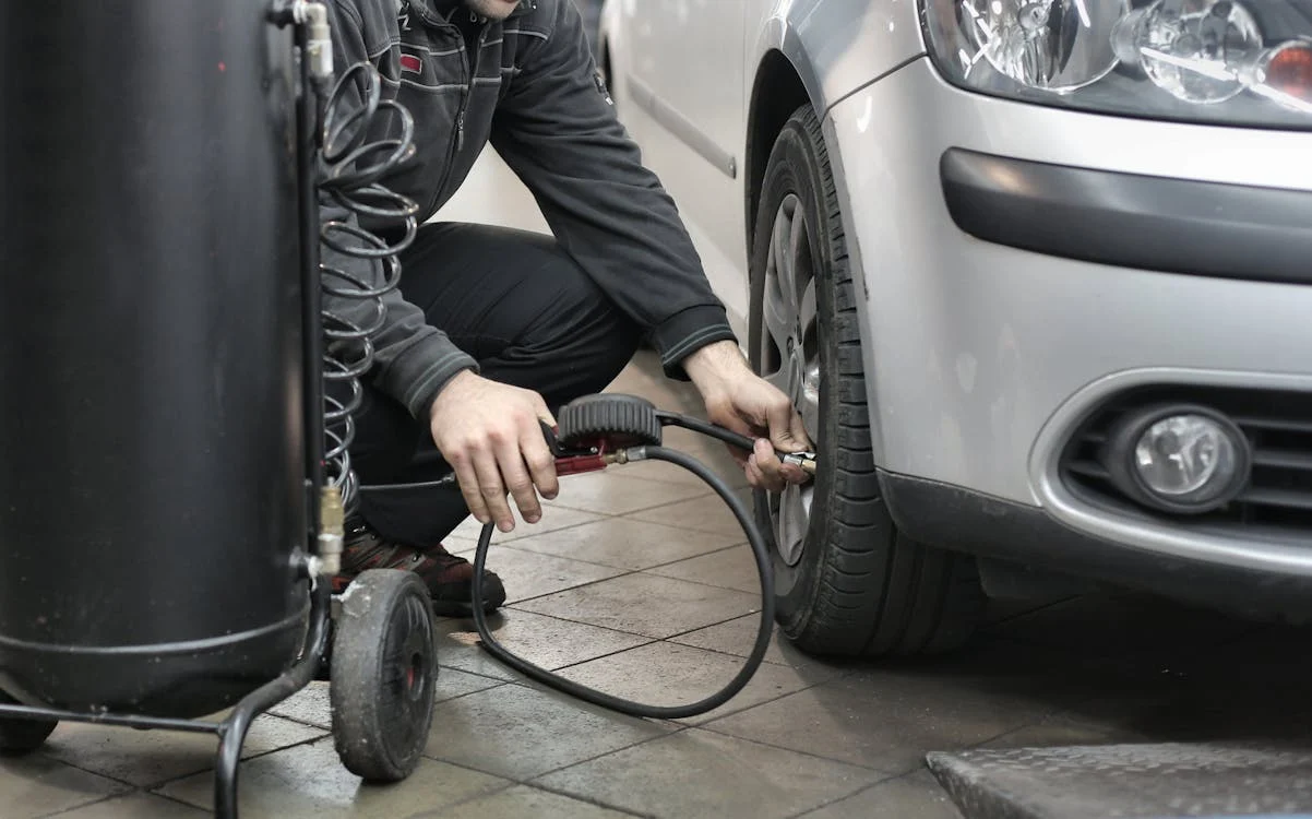 Technician fixing a flat tire on a silver car at Black n Rounds ATX.