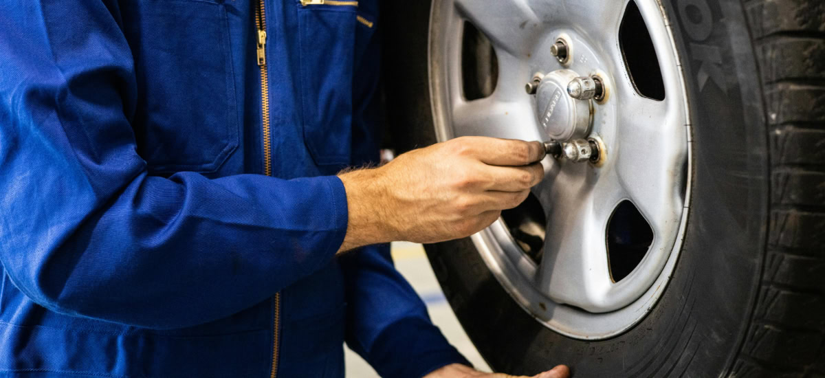 Technician inspecting tire pressure and lug nuts for optimal vehicle performance.
