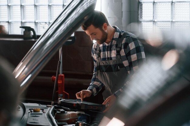 Engine diagnostics technician inspecting vehicle's electrical system for issues.