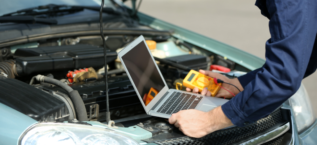 Auto repair technician diagnosing vehicle issues with electronic tools under the hood.