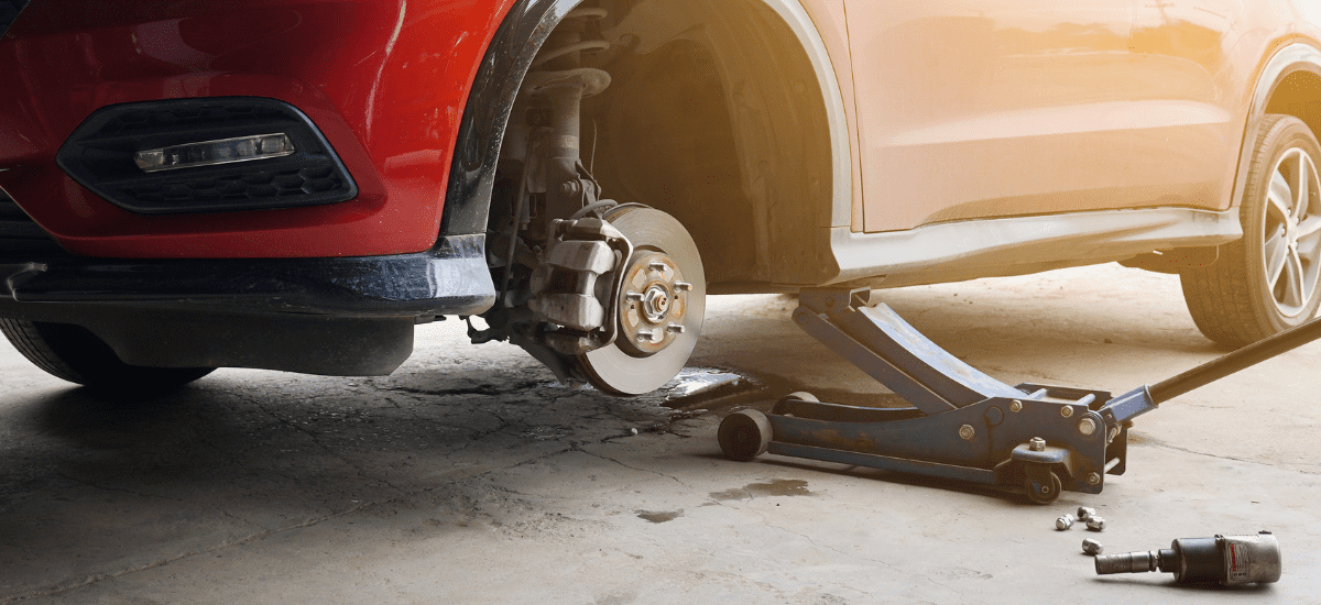 Car with missing wheel, undergoing brake repair at Bluestone Automotive.