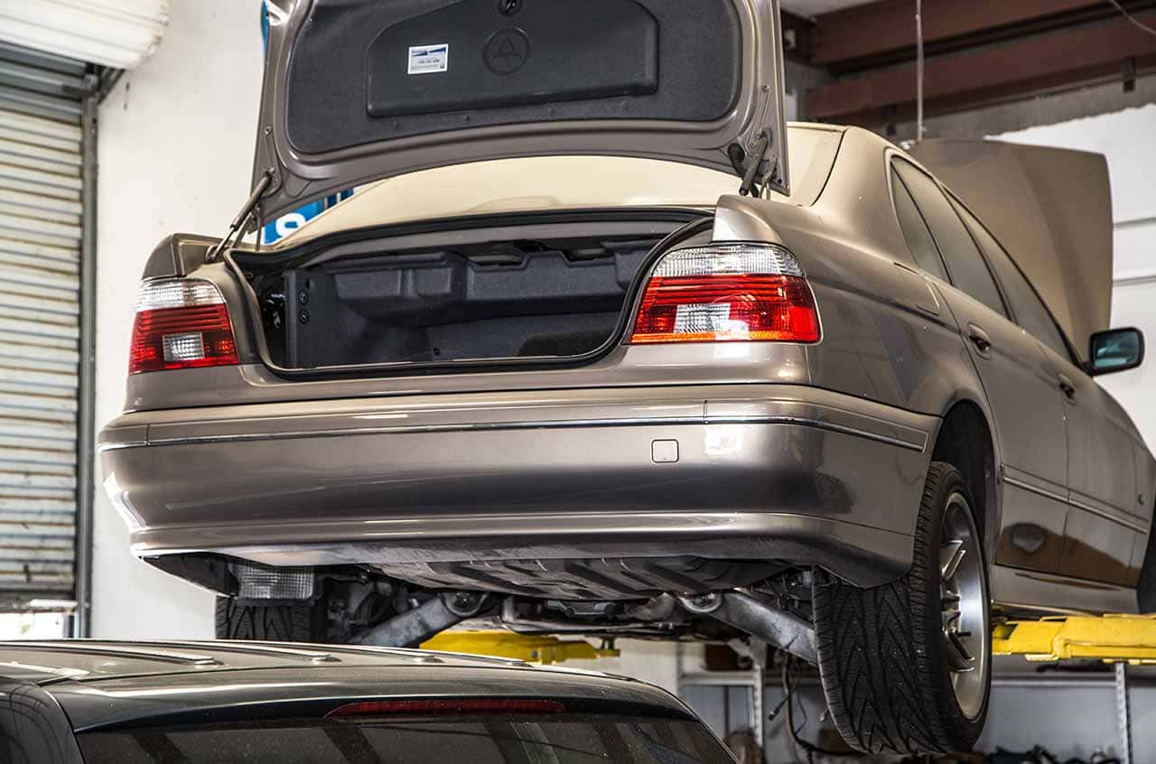BMW 3 Series with open trunk on lift at BMP Auto Service, vehicle maintenance and repair experts.