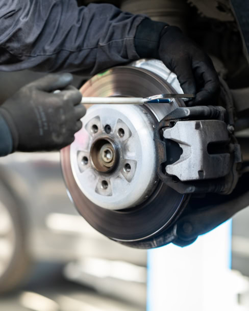 Technician inspecting brake rotor during brake system check.
