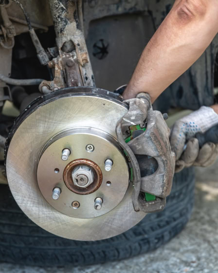 Technician inspecting brake rotor during brake system check.