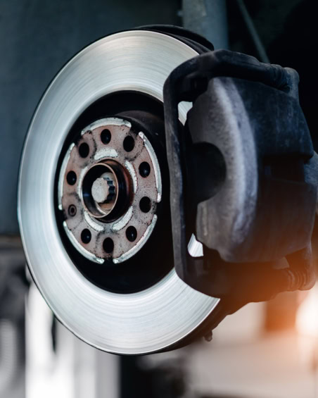 Close-up of a car brake rotor and caliper during replacement process.