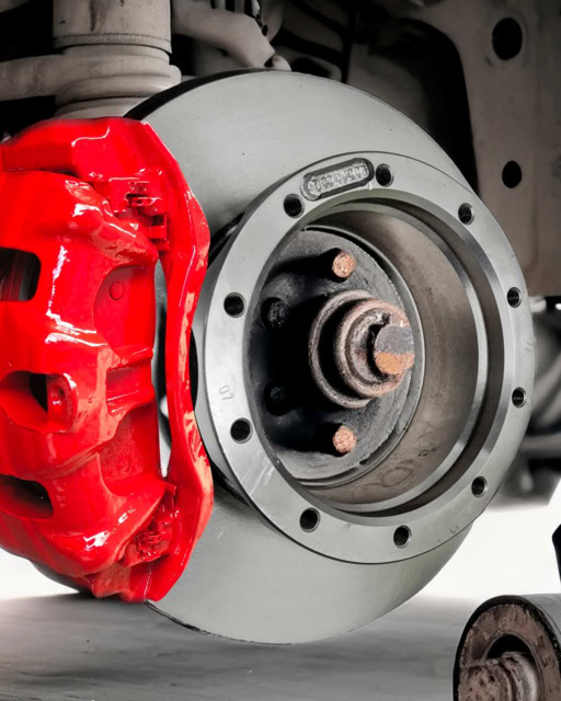 Close-up of brake rotor and red brake caliper during replacement.
