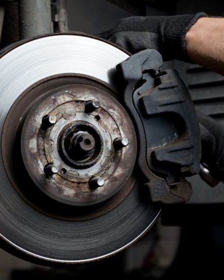 Close-up of a car brake disc and caliper during repair at BMP Auto Service.