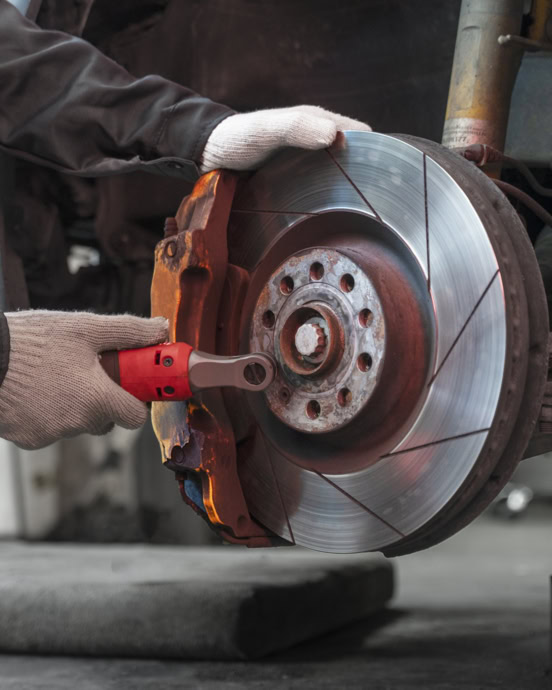 Technician replacing brake pads on a vehicle's disc brake system.