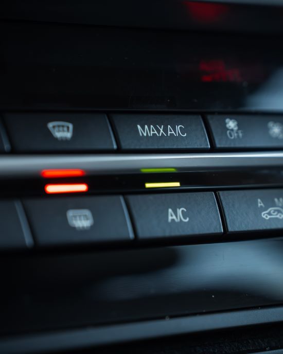 Car climate control panel with AC and defrost buttons.