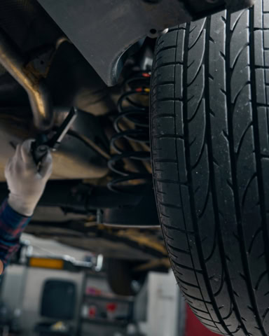 Close-up of car suspension and tire during repair at BMP Auto Service.