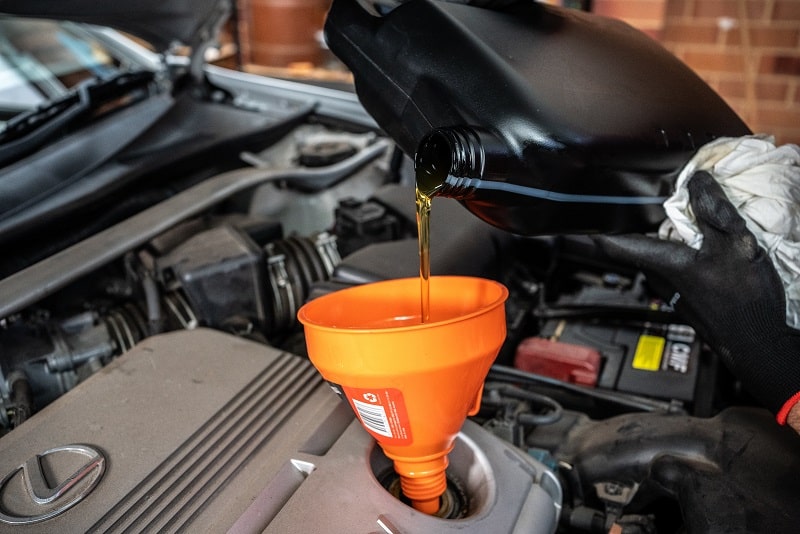 Engine oil being poured into a car engine during an oil change service.