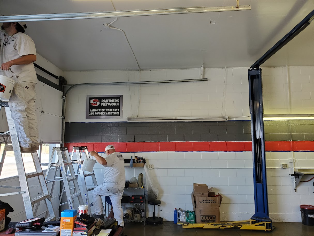 Auto repair shop with technicians working on vehicle exhaust systems and mufflers.