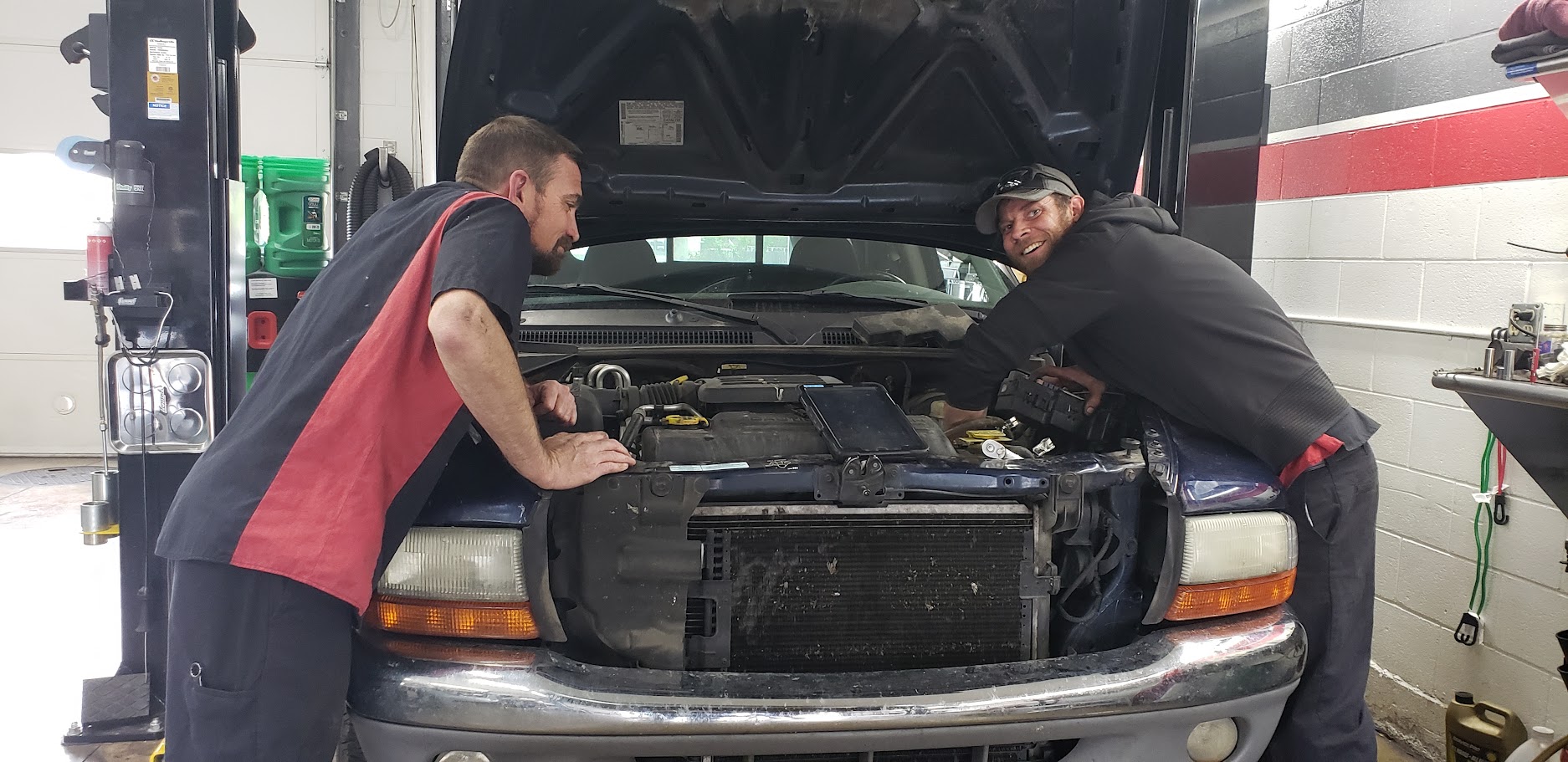 Auto technicians inspecting vehicle engine.