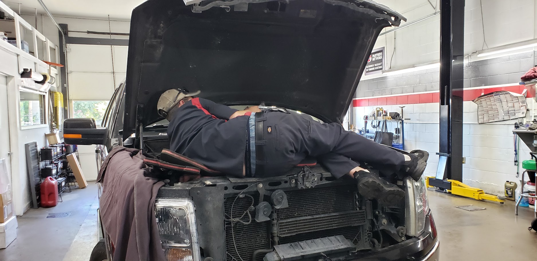 Auto mechanic inspecting vehicle engine under the hood.