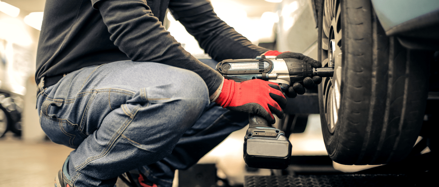 Technician installing a car muffler with power tools at Boise Muffler Auto Repair.