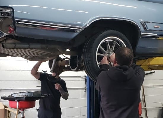Technicians working on a car's wheel during auto repair at Boise Muffler.