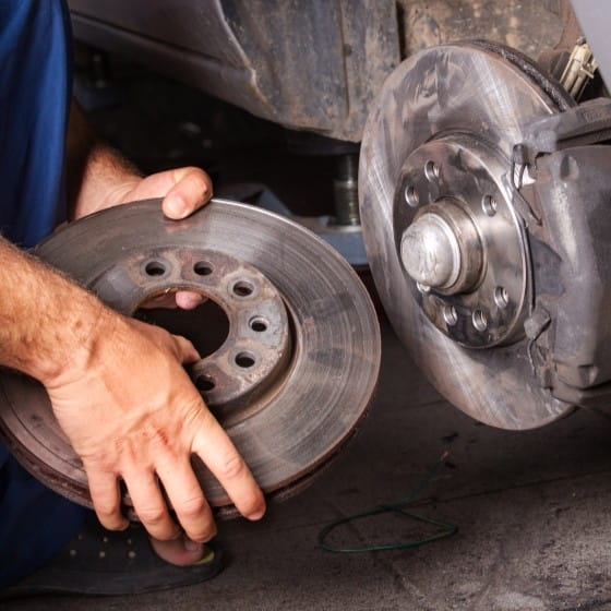Mechanic replacing brake rotor on vehicle at Boise Muffler Auto Repair shop.