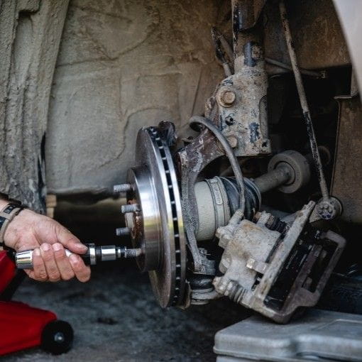 Mechanic inspecting and repairing a vehicle's wheel hub assembly.