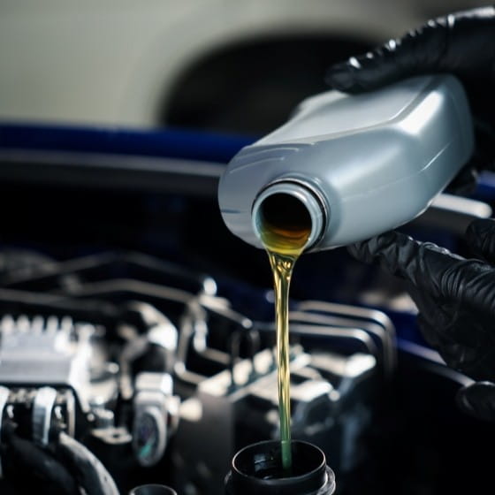 Technician pouring engine oil during vehicle maintenance at Boise Muffler Auto Repair.