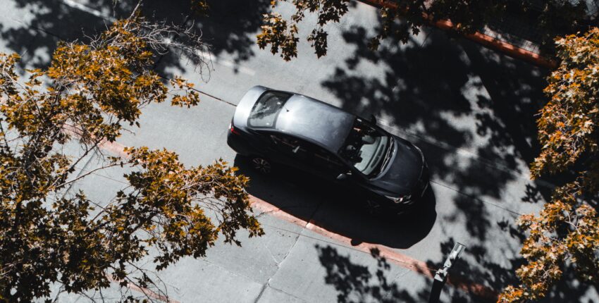 Black car parked on street with trees and shadows in Boise.