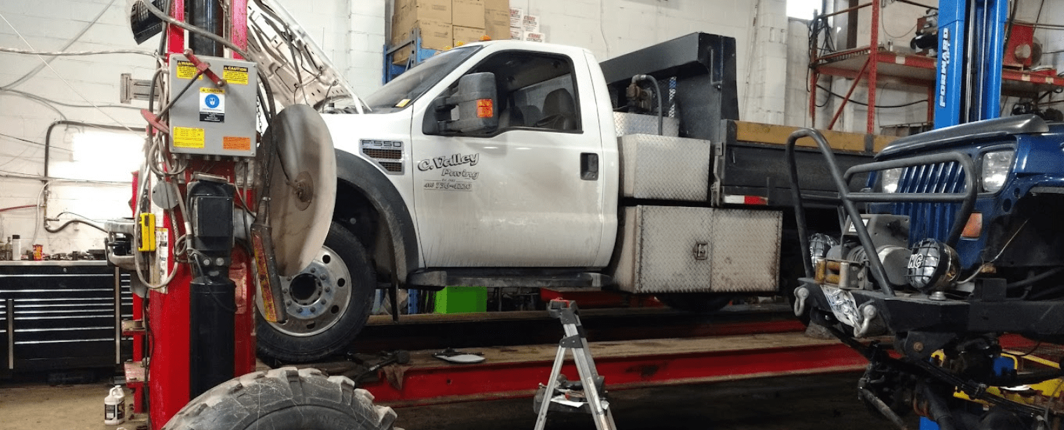 Vehicle alignment technician working on a truck in a professional garage.