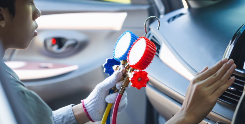 Technician inspecting car air conditioning system for repairs.