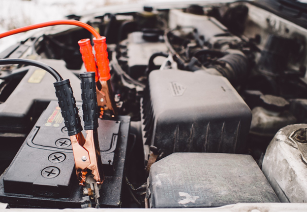 Car battery with jumper cables showing signs of wear and corrosion.
