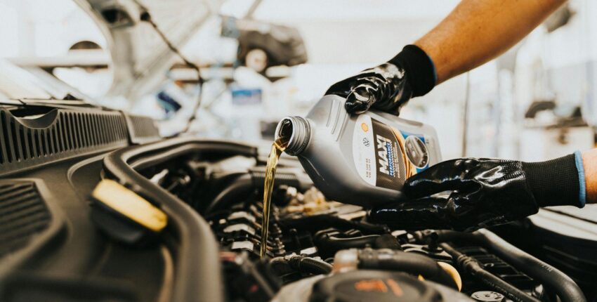 Engine oil being poured into a car engine during maintenance.