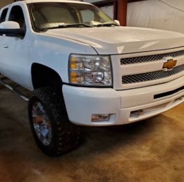 White Chevrolet Silverado offroad truck with custom tires.