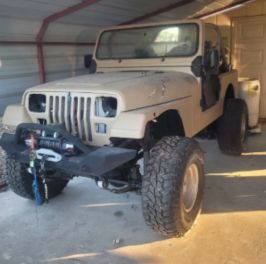 Classic white Jeep Wrangler offroad vehicle with upgraded tires and winch.