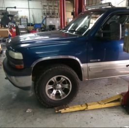 Blue offroad truck in workshop with tools and equipment.