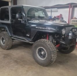Custom offroad Jeep with lifted suspension and large tires for rugged terrain.