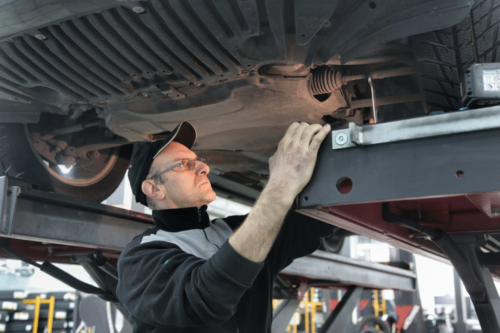 Engine diagnostics technician inspecting under vehicle for check engine light issues.