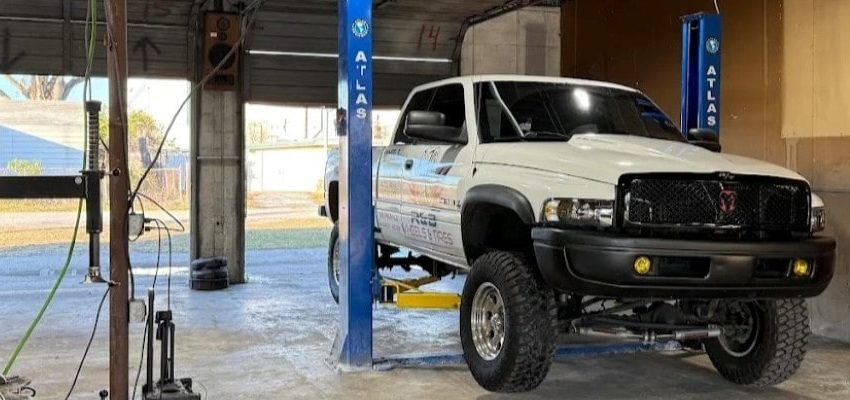 Automotive repair shop with lifted truck on a hydraulic lift inside a garage.