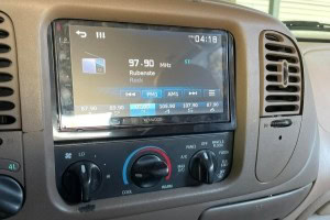 Modern vehicle dashboard featuring radio, climate controls, and display screen at Burton’s Automotiv.