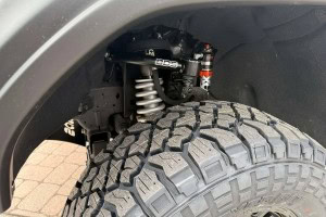 Heavy-duty off-road vehicle suspension with large tire and shock absorber at Burton’s Automotive.