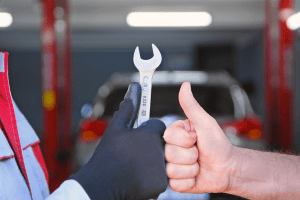 Mechanic holding a wrench giving a thumbs-up at Butterworth's Service Centre.
