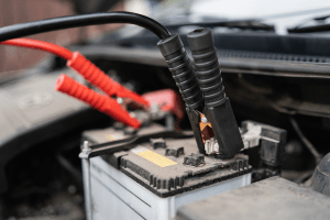 Battery testing and maintenance under the hood of a vehicle.