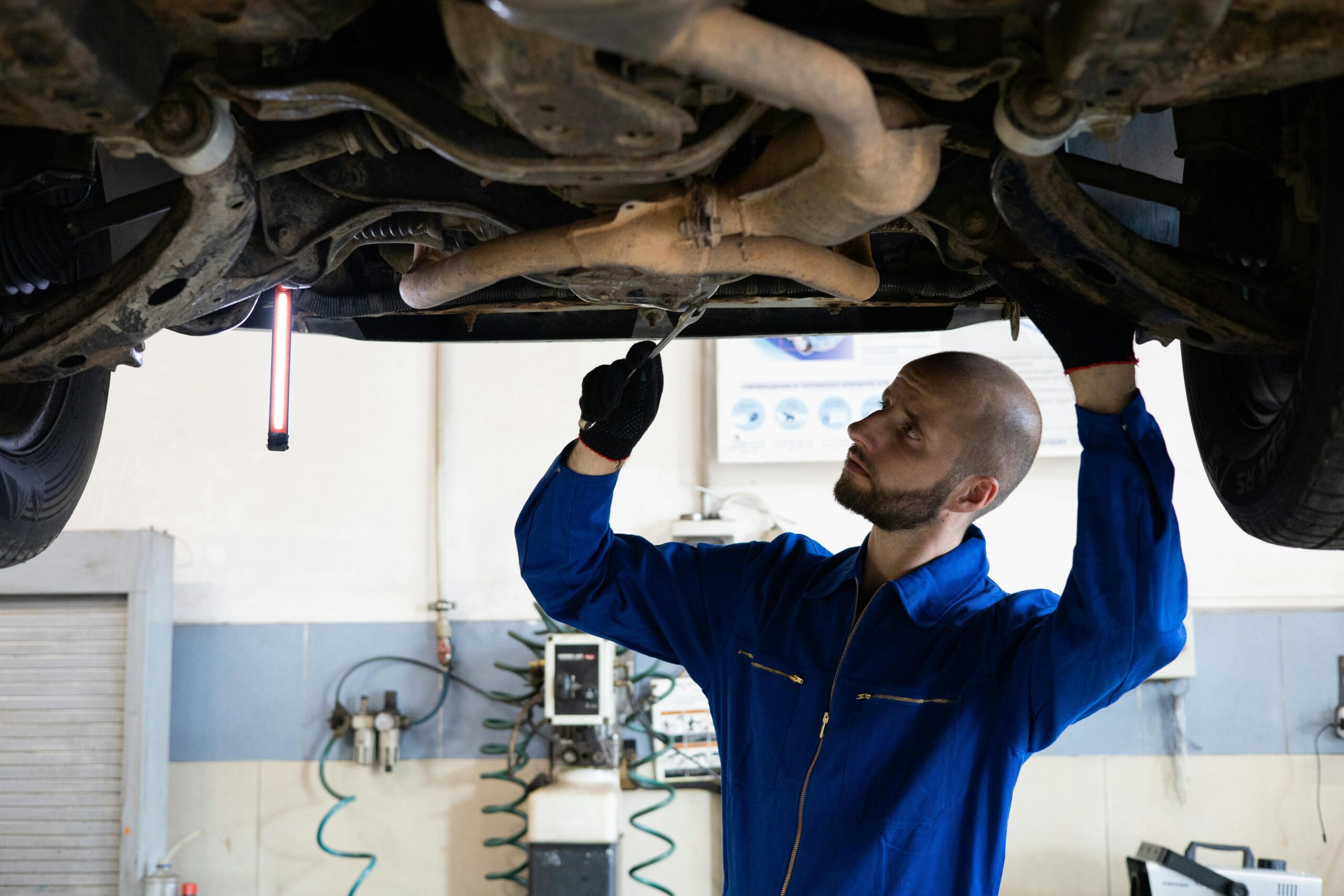 Technician inspecting vehicle undercarriage for rustproofing application.