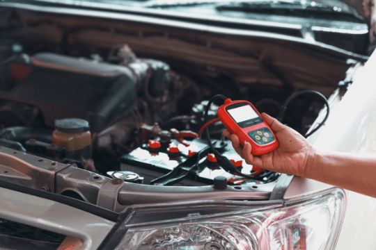 Handheld diagnostic scanner testing a vehicle engine system.