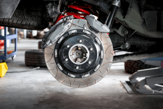 Car brake disc and caliper being serviced at auto shop.