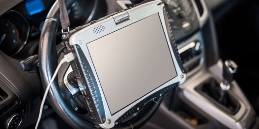 Diagnostic scanner device on car dashboard for vehicle repair and maintenance.