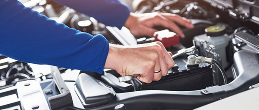 Auto mechanic inspecting engine components under the hood.