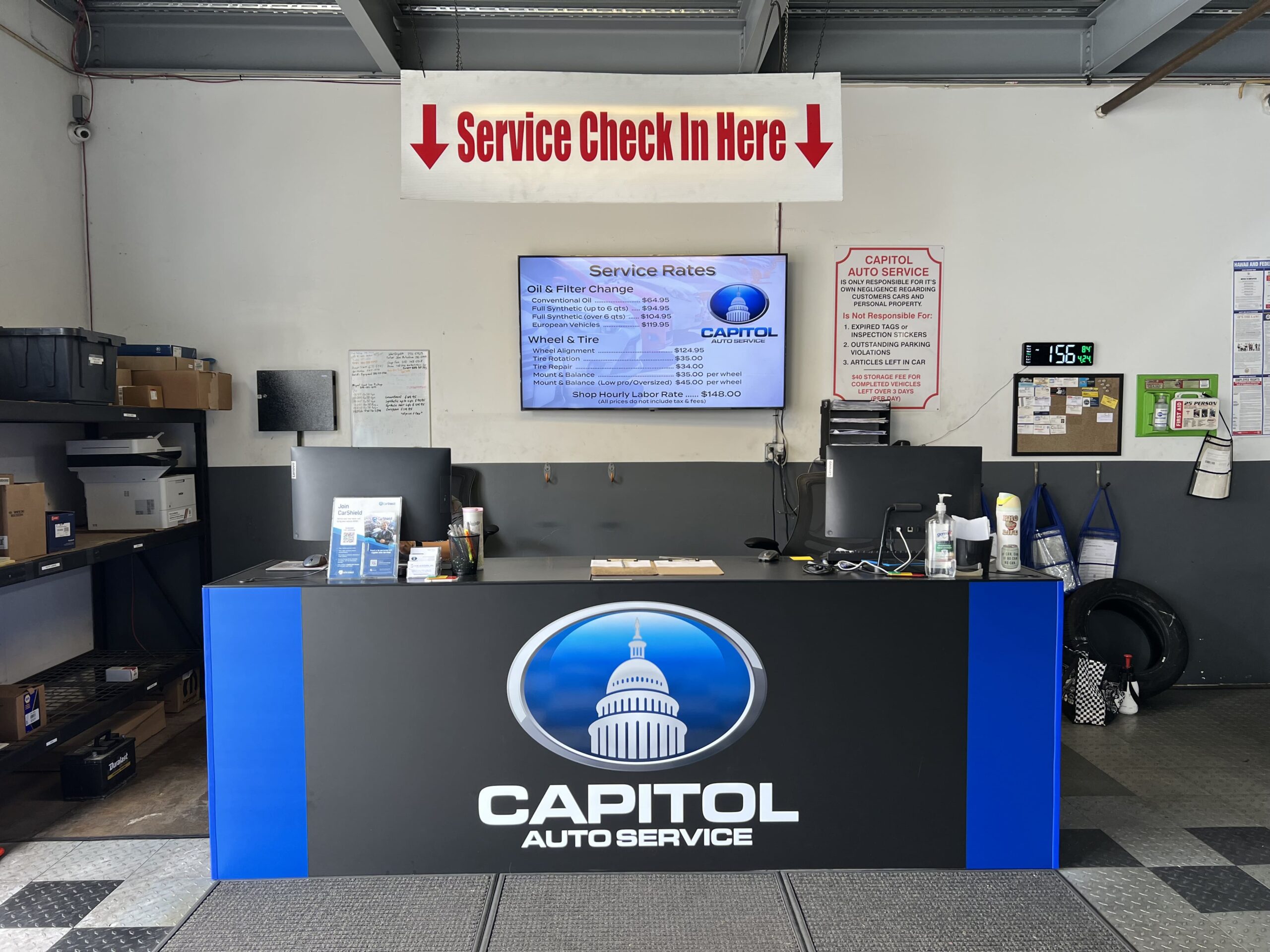 Capitol Auto Service reception area with service check-in sign and digital display.