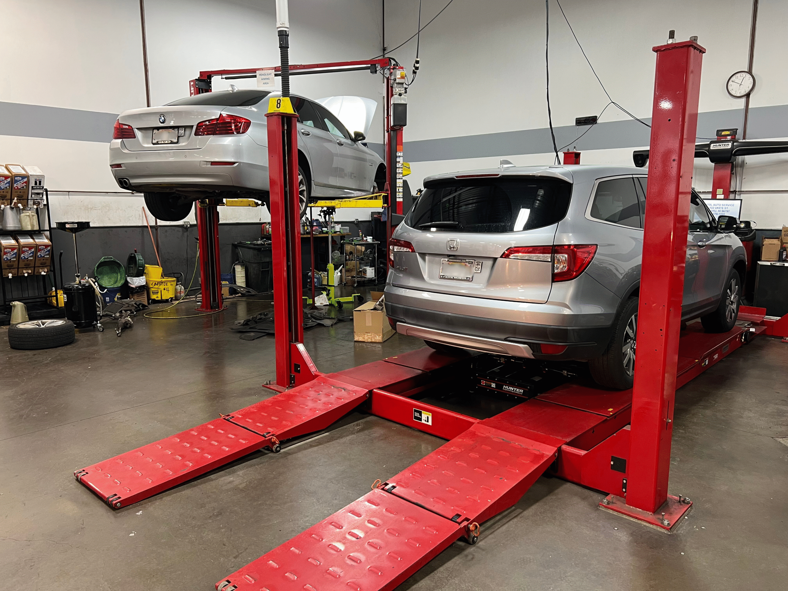 Auto repair shop with two vehicles on hydraulic lifts for maintenance and repairs.