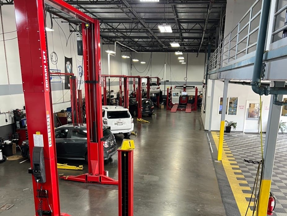 Auto repair shop with vehicle lifts, tools, and cars in a spacious, well-lit service area.