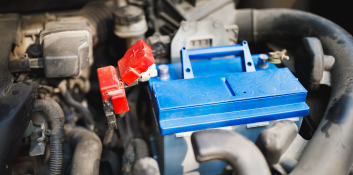 Car battery being replaced in engine bay during maintenance.