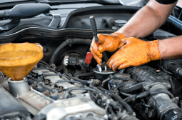 Technician working on a diesel engine with tools in a garage setting.