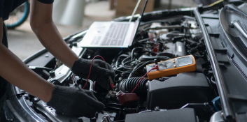 Technician performing engine diagnostics with diagnostic tools on a car engine.