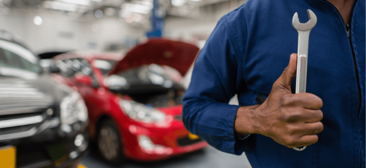 Automotive repair technician holding a wrench in a busy garage.